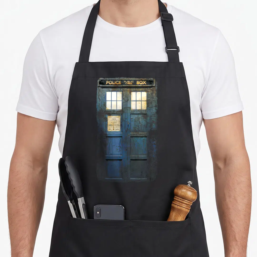 Traveller distressed apron - Weathered blue police box with yellow POLICE PUBLIC CALL BOX sign text — shown on a black cotton canvas apron against a white background