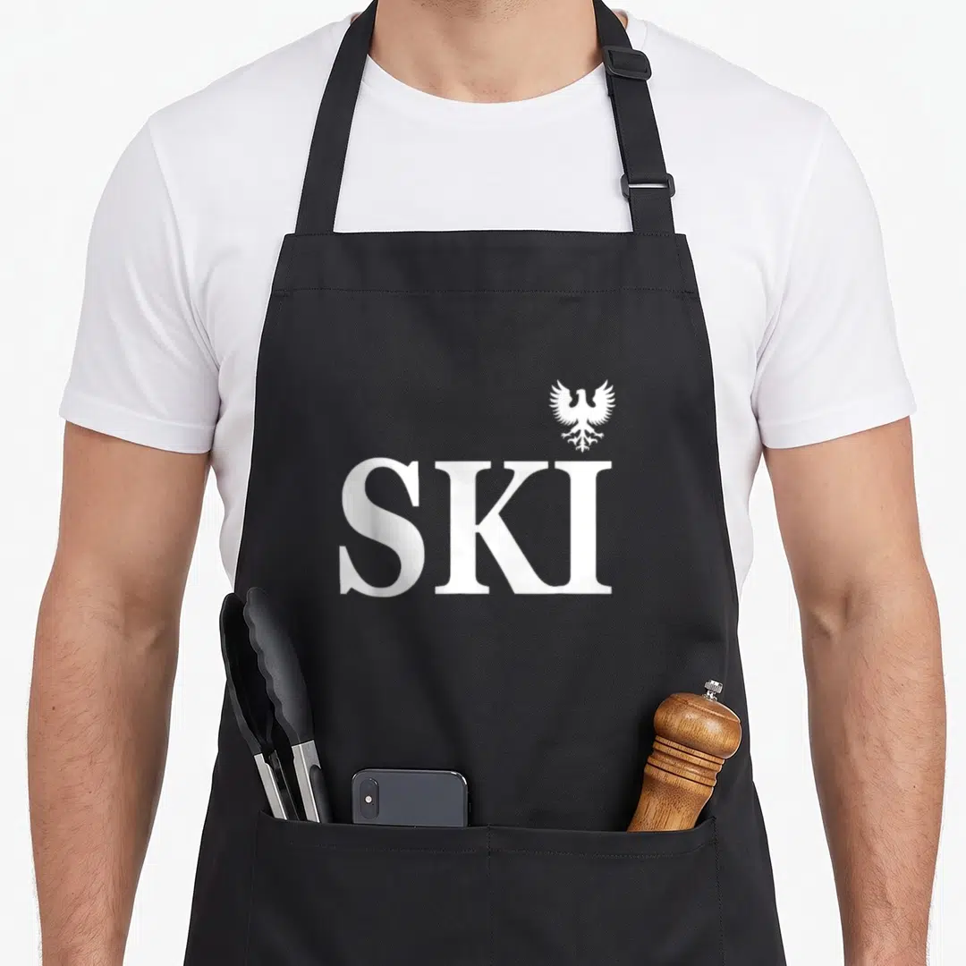 Heritage polish aprons - White SKI text with small eagle symbol above the letter I — shown on a black cotton canvas apron against a white background