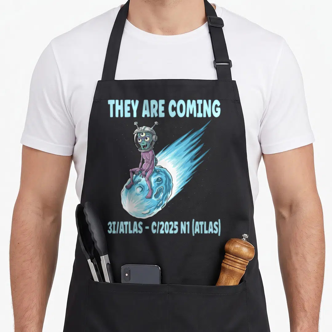 Alien atlas apron - Cartoon alien sitting on blue comet with 3I/ATLAS text on grey background — shown on a black cotton canvas apron against a white background