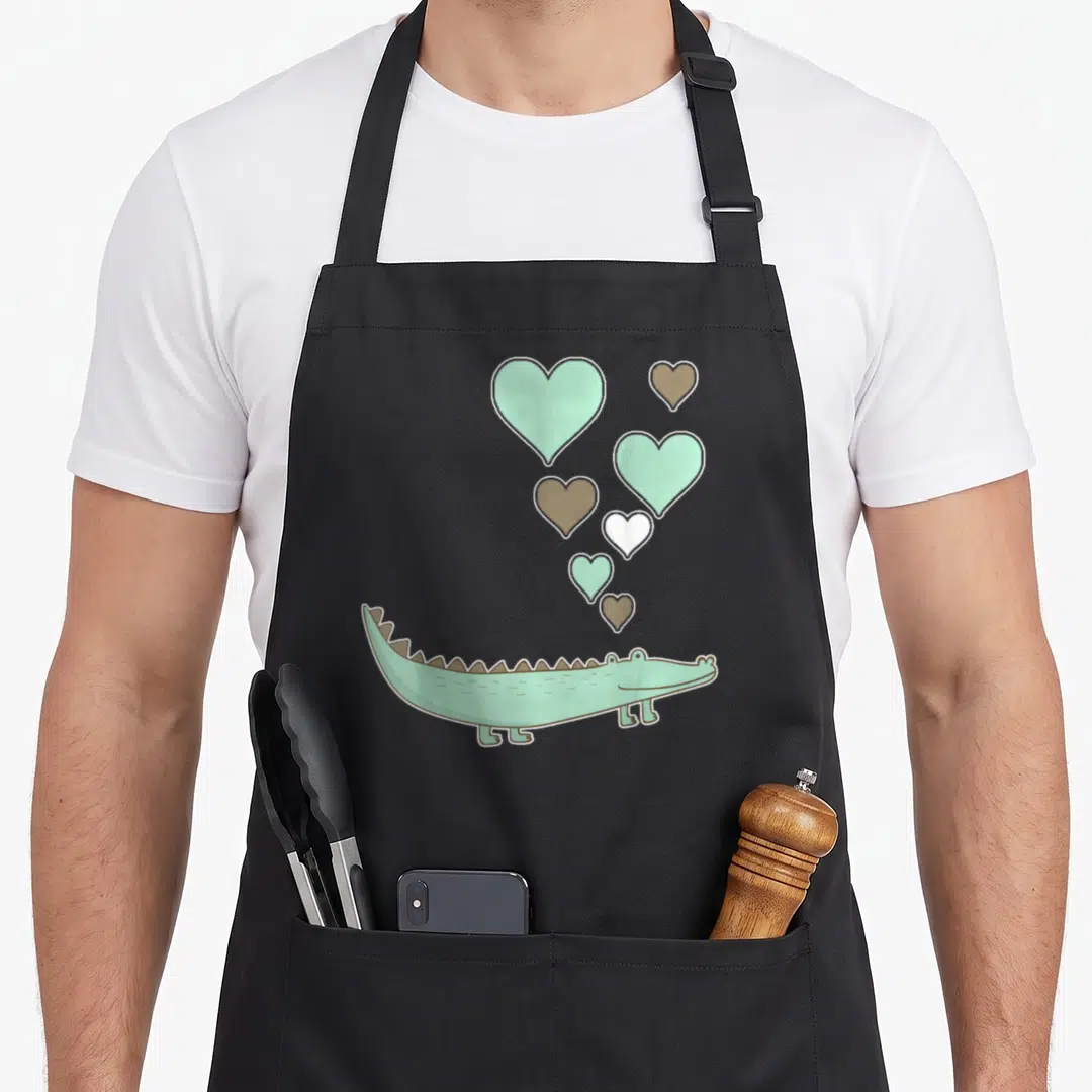 Vintage alligator apron - Cartoon mint crocodile with six floating hearts in mint, brown, and white — shown on a black cotton canvas apron against a white background