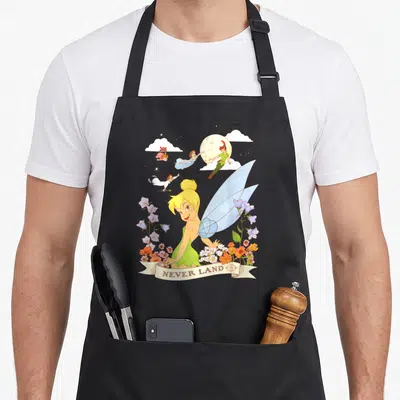 Land bell apron - Tinker Bell among flowers with Peter Pan flying and NEVER LAND banner text — shown on a black cotton canvas apron against a white background