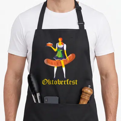Barmaid german apron - Cartoon woman in blue dirndl holding beer tray behind giant brown sausage with yellow — shown on a black cotton canvas apron against a white background