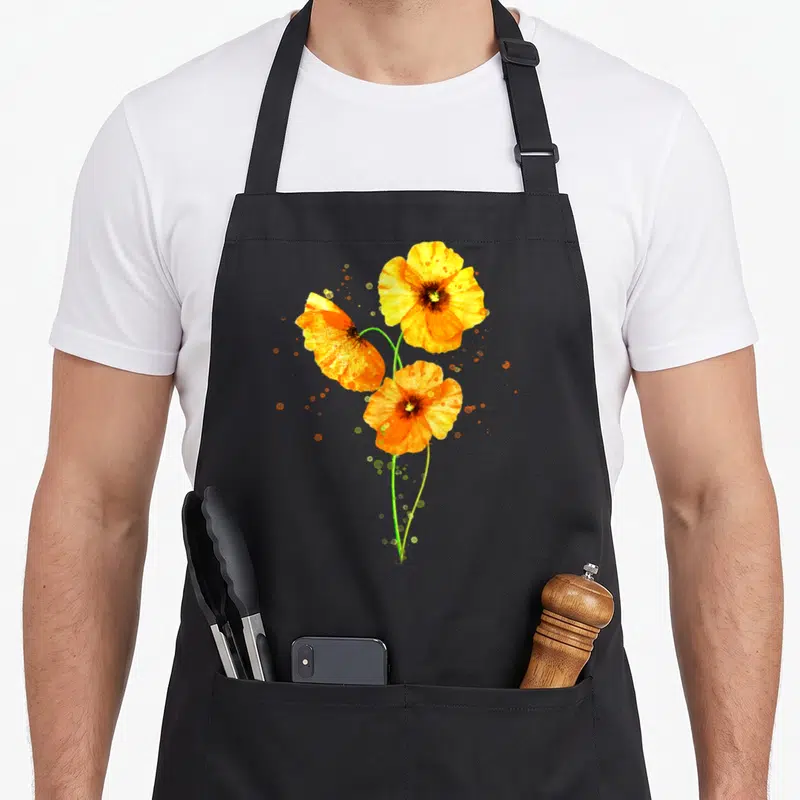 Poppy orange california apron - Three orange and yellow watercolor poppies on green stems with scattered paint splatters — shown on a black cotton canvas apron against a white background