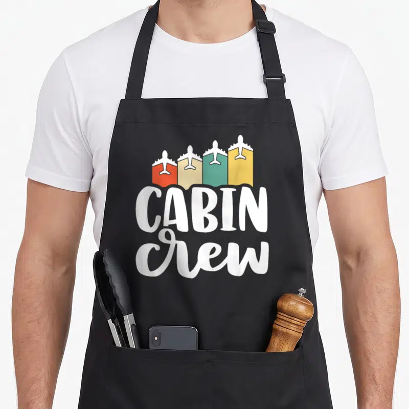 Cabin crew apron - Four airplanes in red beige green yellow blocks above stacked white cabin crew text — shown on a black cotton canvas apron against a white background