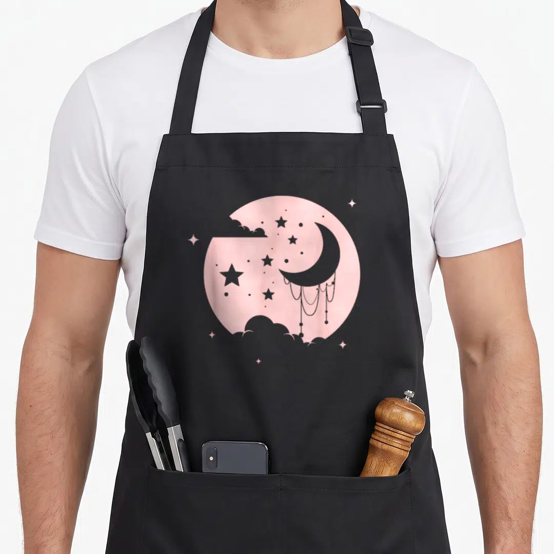 Goth kawaii apron - Pink circle with grey crescent moon, hanging beads, stars, and clouds — shown on a black cotton canvas apron against a white background