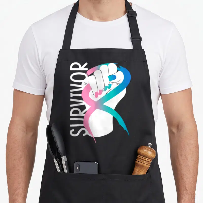 Month thyroid apron - Vertical survivor text beside a white fist gripping a pink blue and teal gradient ribbon — shown on a black cotton canvas apron against a white background