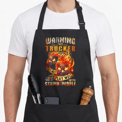 Warning stupid aprons - Flaming skull with WARNING THIS TRUCKER DOES NOT PLAY WELL WITH STUPID PEOPLE text — shown on a black cotton canvas apron against a white background