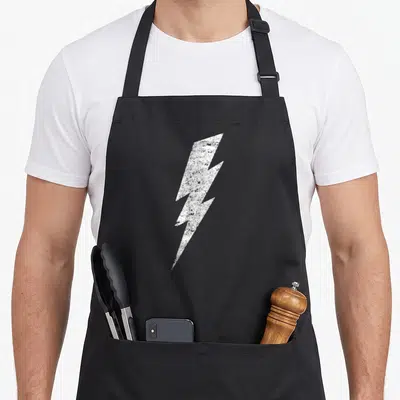 Bold distressed apron - White distressed lightning bolt graphic centered on black fabric — shown on a black cotton canvas apron against a white background