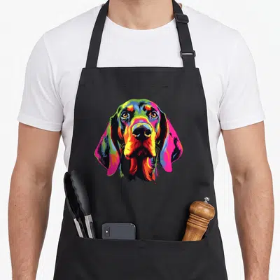 Watercolor dog apron - Multicolored cartoon dog head in blue green yellow red pink purple with two front pockets — shown on a black cotton canvas apron against a white background