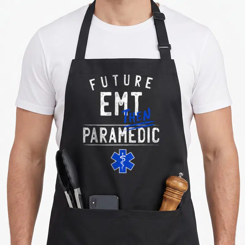 Emt future class apron - Future EMT Then Paramedic text and blue Star of Life symbol — shown on a black cotton canvas apron against a white background