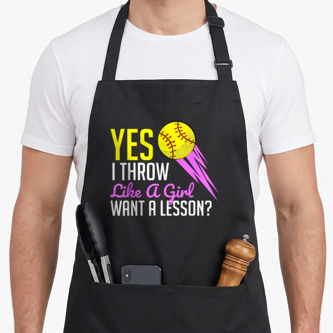 Softball player game aprons - Yes I Throw Like A Girl text with yellow softball and pink motion lines — shown on a black cotton canvas apron against a white background