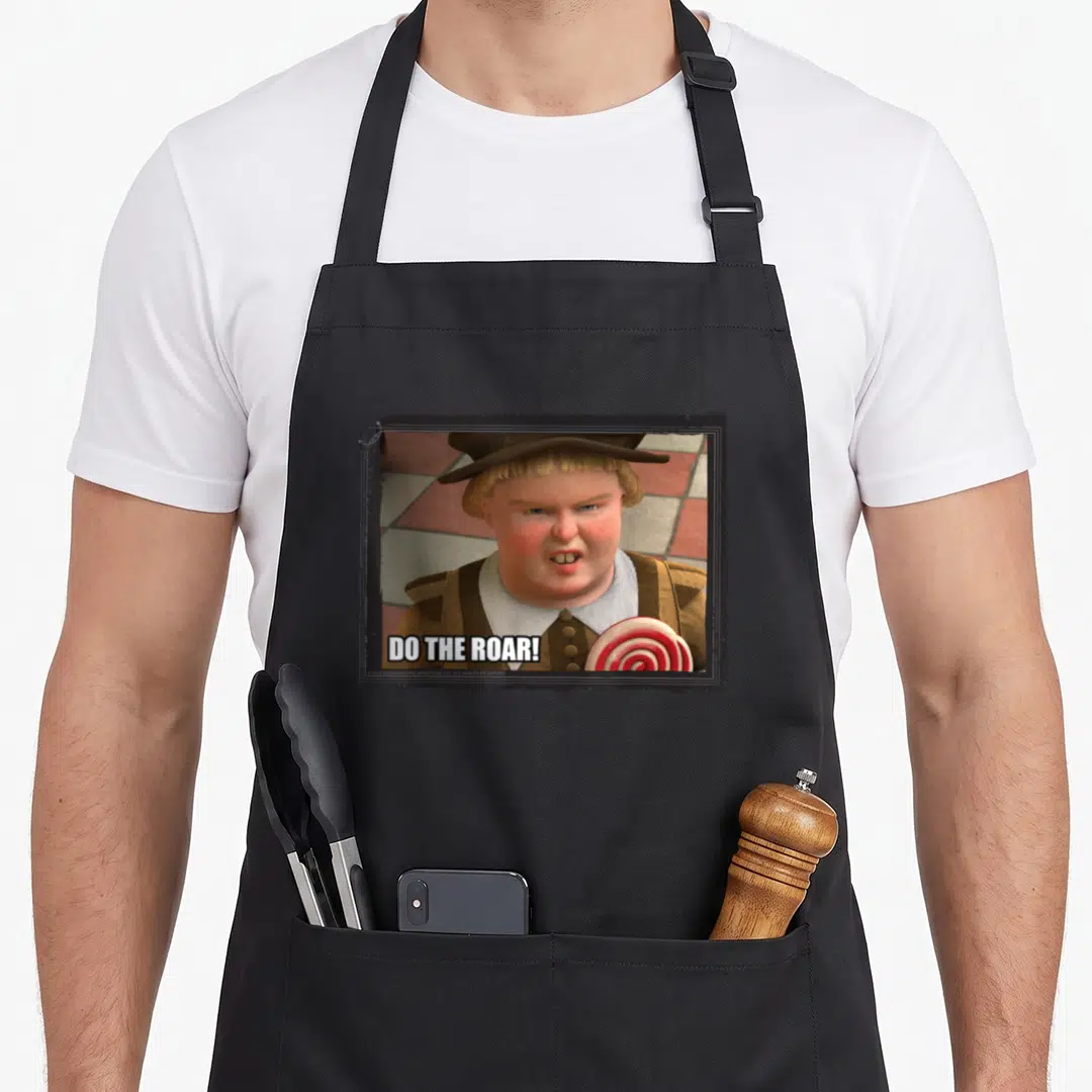 Roar meme apron - Cartoon man with lollipop and DO THE ROAR text in brown and red frame — shown on a black cotton canvas apron against a white background