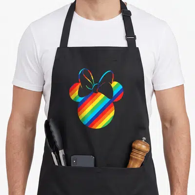 Silhouette rainbow apron - Mouse head silhouette filled with diagonal red orange yellow green blue purple stripes — shown on a black cotton canvas apron against a white background