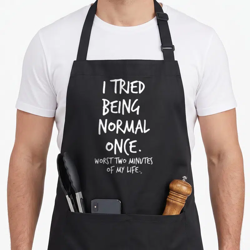 Tried only once apron - White stacked text reading I Tried Being Normal Once Worst Two Minutes of My Life — shown on a black cotton canvas apron against a white background