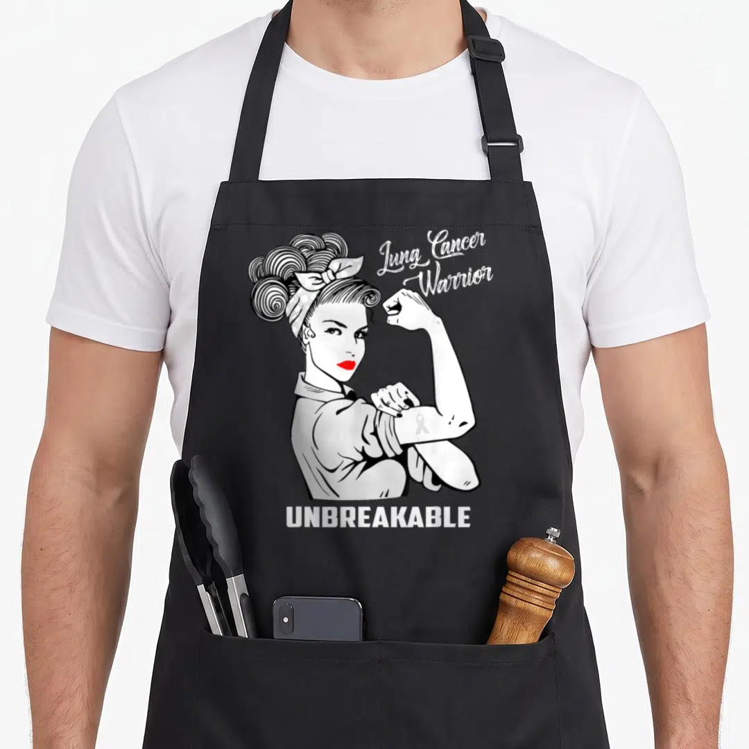 Cancer lungs apron - Cartoon woman flexing arm with ribbon, Lung Cancer Warrior UNBREAKABLE text — shown on a black cotton canvas apron against a white background