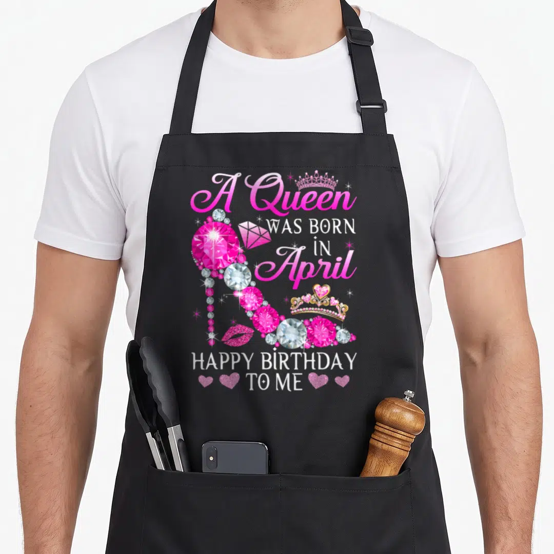 Heel baking queen apron - Diamond high heel shoe with A Queen Was Born In April text and crown accents in pink — shown on a black cotton canvas apron against a white background