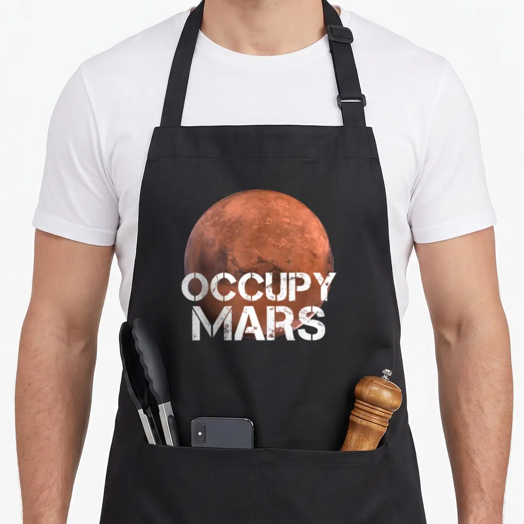 Occupy space apron - Reddish-brown Mars planet with white stacked stencil text reading OCCUPY MARS — shown on a black cotton canvas apron against a white background
