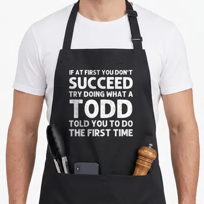 Todd family reunion aprons - White distressed text reading IF AT FIRST YOU DON'T SUCCEED TRY DOING WHAT A TODD TOLD YOU — shown on a black cotton canvas apron against a white background