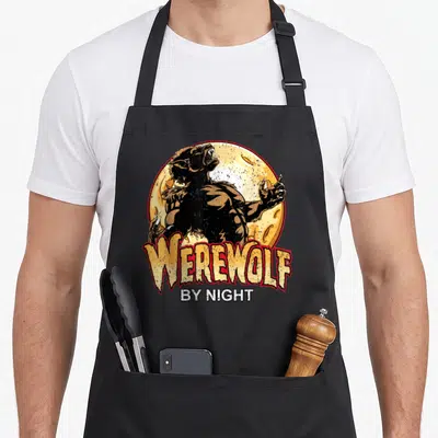 Night werewolf apron - Cartoon werewolf roaring before yellow moon with WEREWOLF BY NIGHT text in red and white — shown on a black cotton canvas apron against a white background