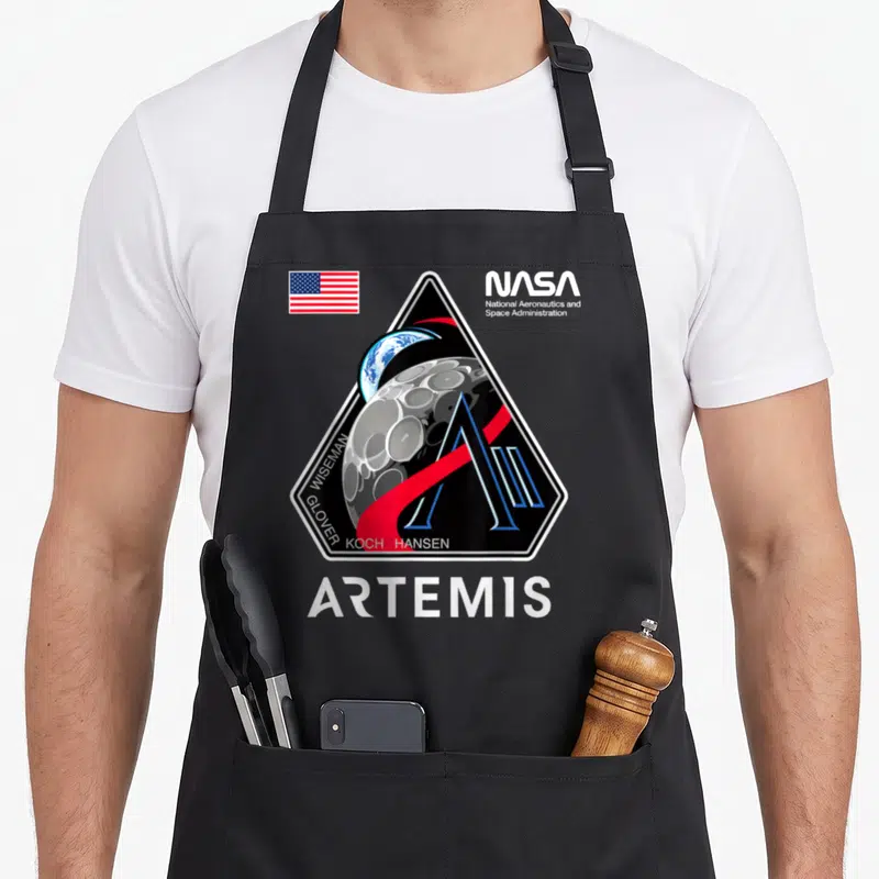 Patch nasa apron - Artemis mission patch with Earth moon NASA logo USA flag crew names ARTEMIS text — shown on a black cotton canvas apron against a white background