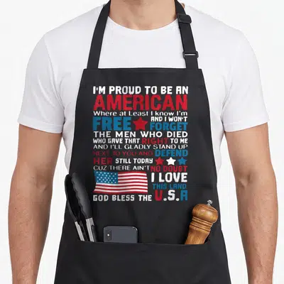 Featuring american flag apron - Stacked patriotic quote with USA flag and red white blue distressed text — shown on a black cotton canvas apron against a white background