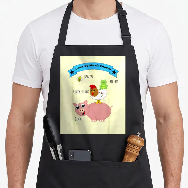 Music farm apron - Country Music Chorus banner with stacked bee frog chicken and pig showing sound effects — shown on a black cotton canvas apron against a white background