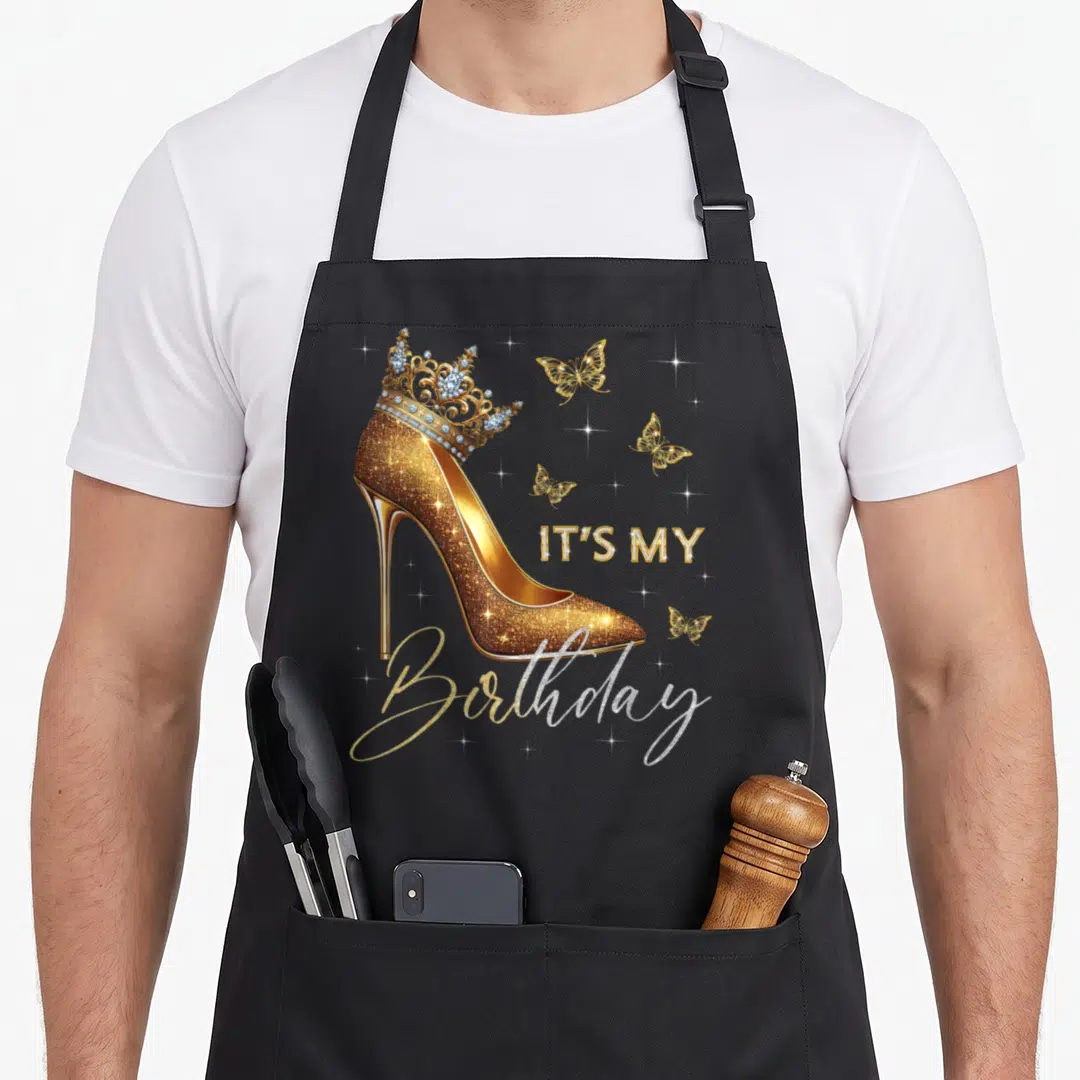 Heel butterfly aprons - Gold glitter high heel with jeweled crown and IT'S MY Birthday text amidst butterflies — shown on a black cotton canvas apron against a white background