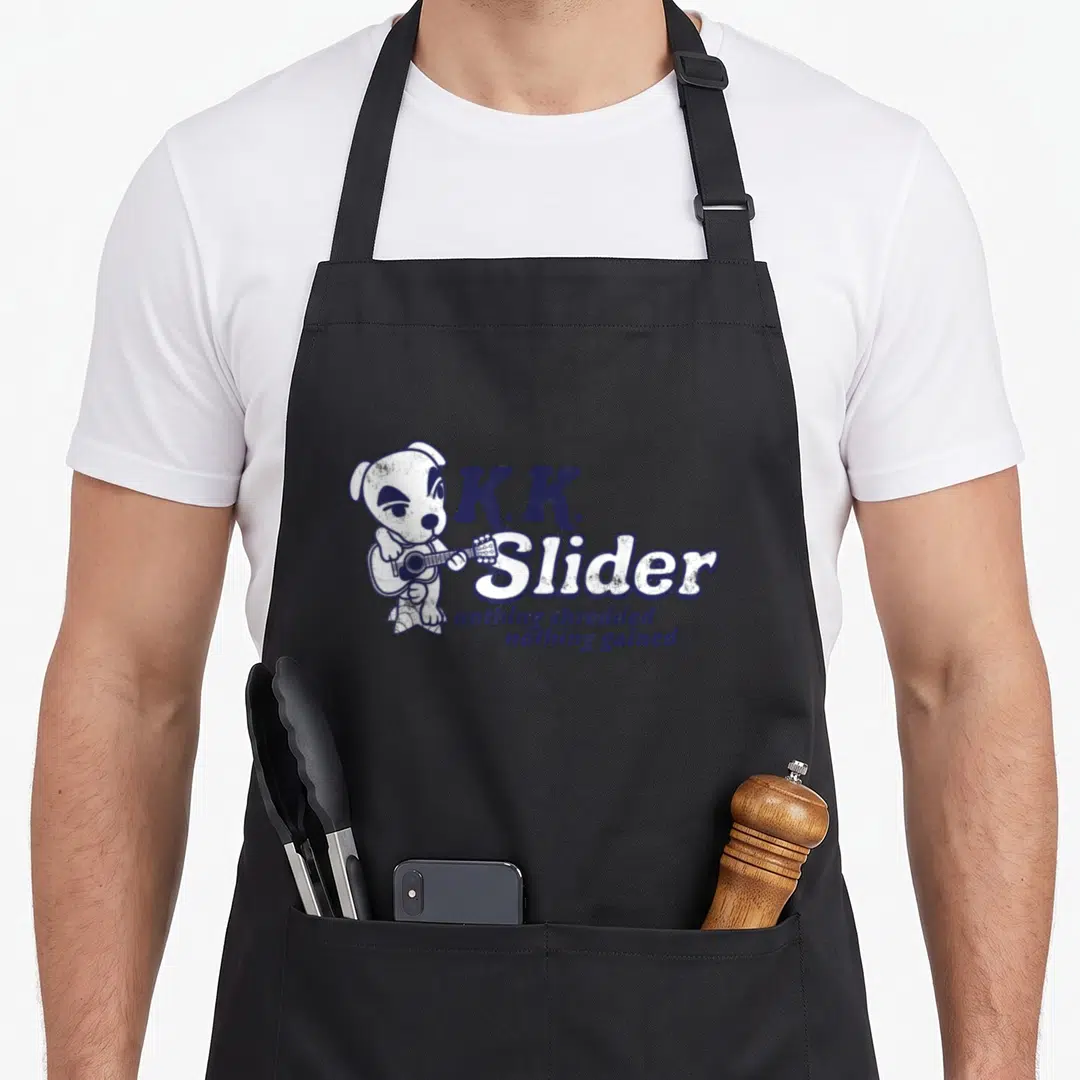 Shredded slides apron - Cartoon dog playing guitar beside stacked blue text reading K.K. Slider nothing shredded — shown on a black cotton canvas apron against a white background