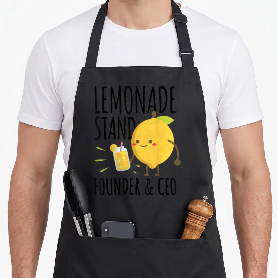 Founder lemonade apron - Cartoon lemon holding drink with LEMONADE STAND FOUNDER CEO text in yellow and black — shown on a black cotton canvas apron against a white background