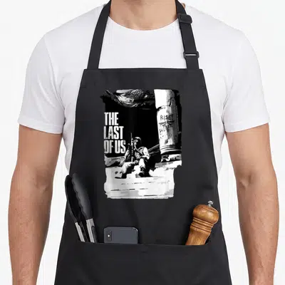 Funny hunter apron - Distressed text reading THE LAST OF US RISE next to a seated gas-masked figure beside a graffiti — shown on a black cotton canvas apron against a white background