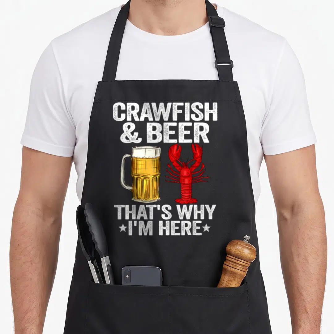 Crawfish daddy apron - Red crawfish and yellow beer mug with white text reading Crawfish & Beer That's Why I'm Here — shown on a black cotton canvas apron against a white background