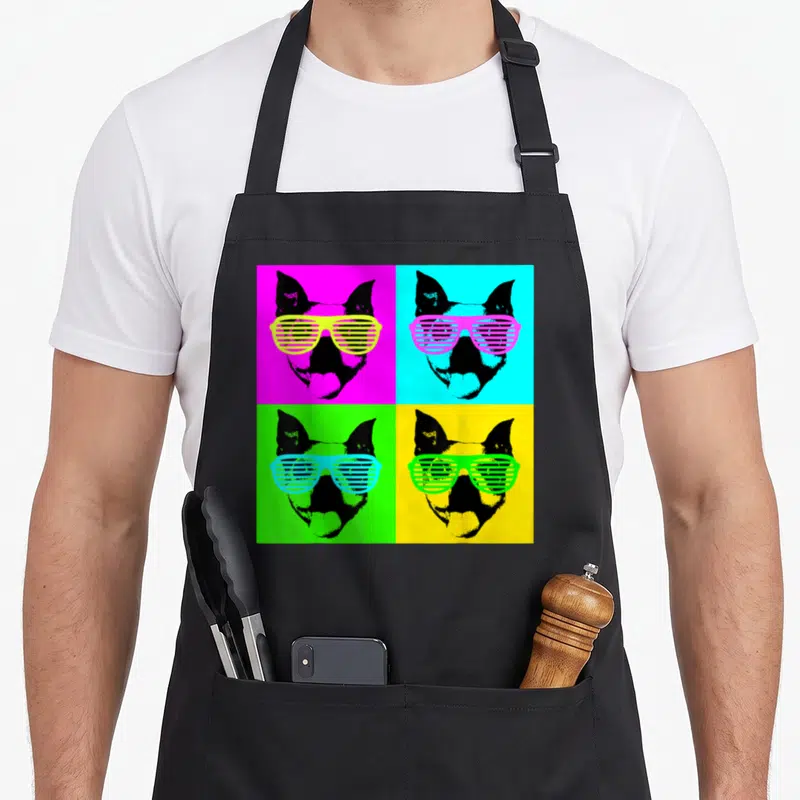 Terrier sunglass dog apron - Four colored squares with black dog heads wearing contrasting shutter shades in pop art — shown on a black cotton canvas apron against a white background