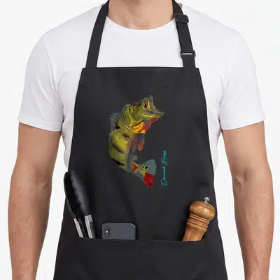 Cute bass fishing aprons - Realistic peacock bass illustration with green yellow red blue colors and vertical light — shown on a black cotton canvas apron against a white background