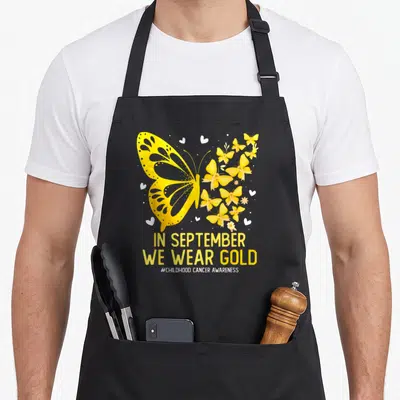 Childhood september girl apron - Large yellow butterfly with smaller ribbon butterflies white hearts flowers — shown on a black cotton canvas apron against a white background