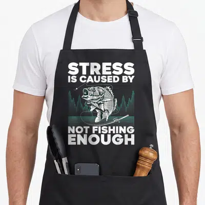 Bass fly fishing aprons - Typography reading Stress Is Caused By Not Fishing Enough above a jumping bass and rod — shown on a black cotton canvas apron against a white background