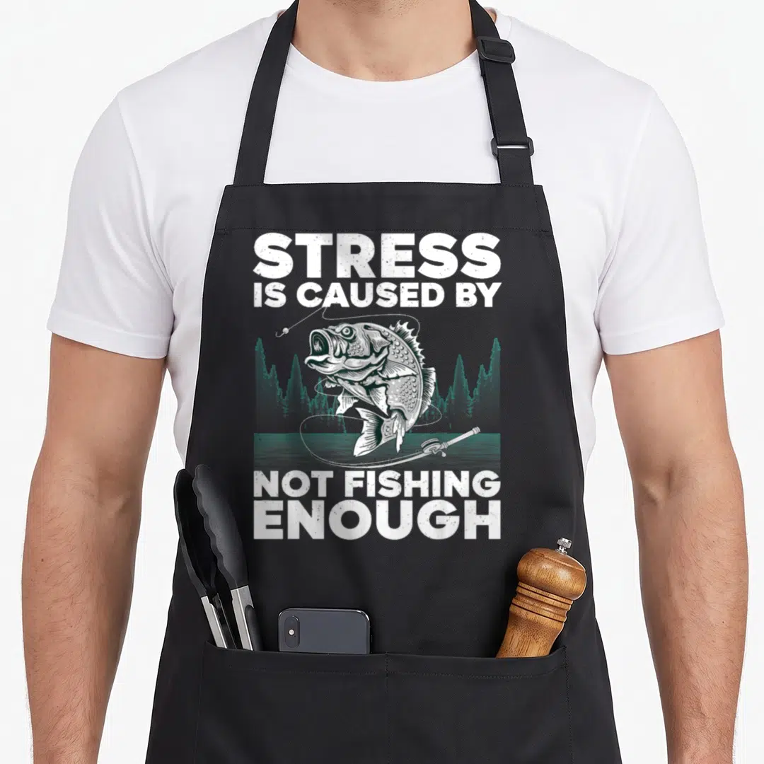 Bass fly fishing aprons - Typography reading Stress Is Caused By Not Fishing Enough above a jumping bass and rod — shown on a black cotton canvas apron against a white background