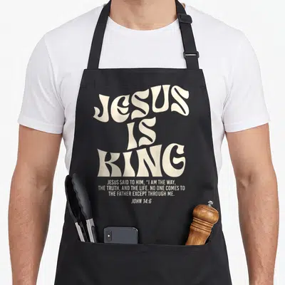 Verse king of the grill apron - Cream typography reading Jesus Is King and John 14:6 verse on grey background — shown on a black cotton canvas apron against a white background