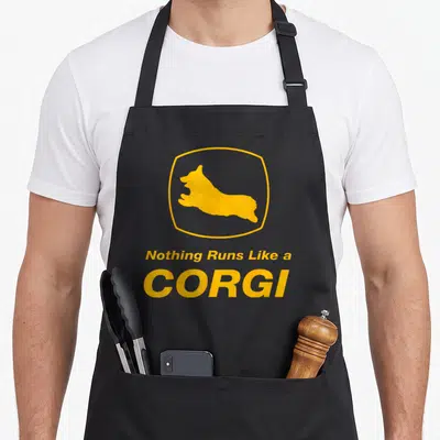 Run corgi apron - Yellow corgi silhouette in hexagon border above stacked text Nothing Runs Like a CORGI — shown on a black cotton canvas apron against a white background