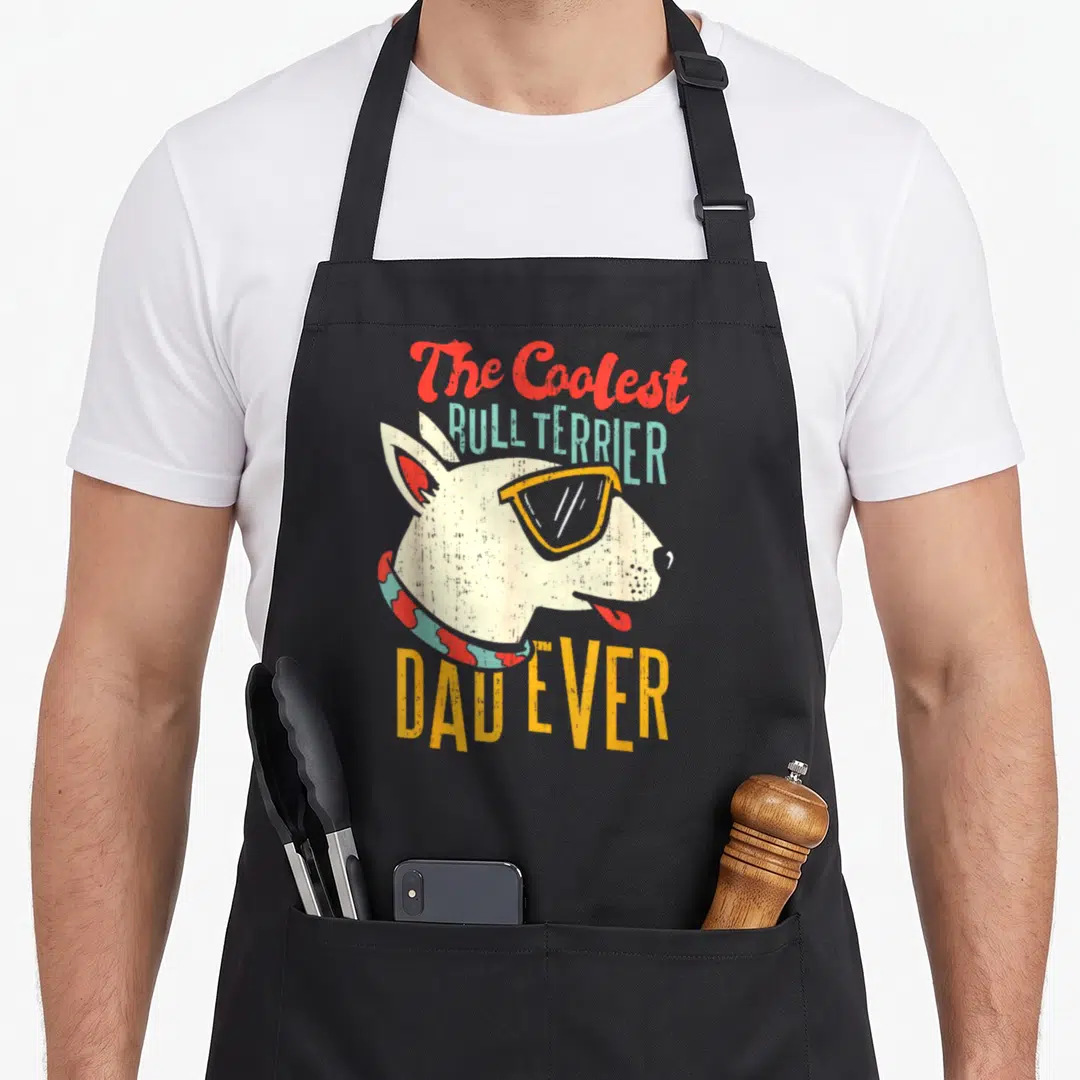 Coolest custom pet apron - Bull terrier head with sunglasses and text The Coolest Bull Terrier Dad Ever in red — shown on a black cotton canvas apron against a white background