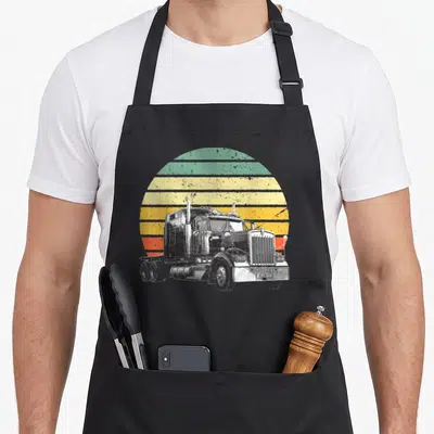 Trucker rig trailer semi truck apron - White semi-truck illustration against a retro sun of horizontal green, yellow — shown on a black cotton canvas apron against a white background