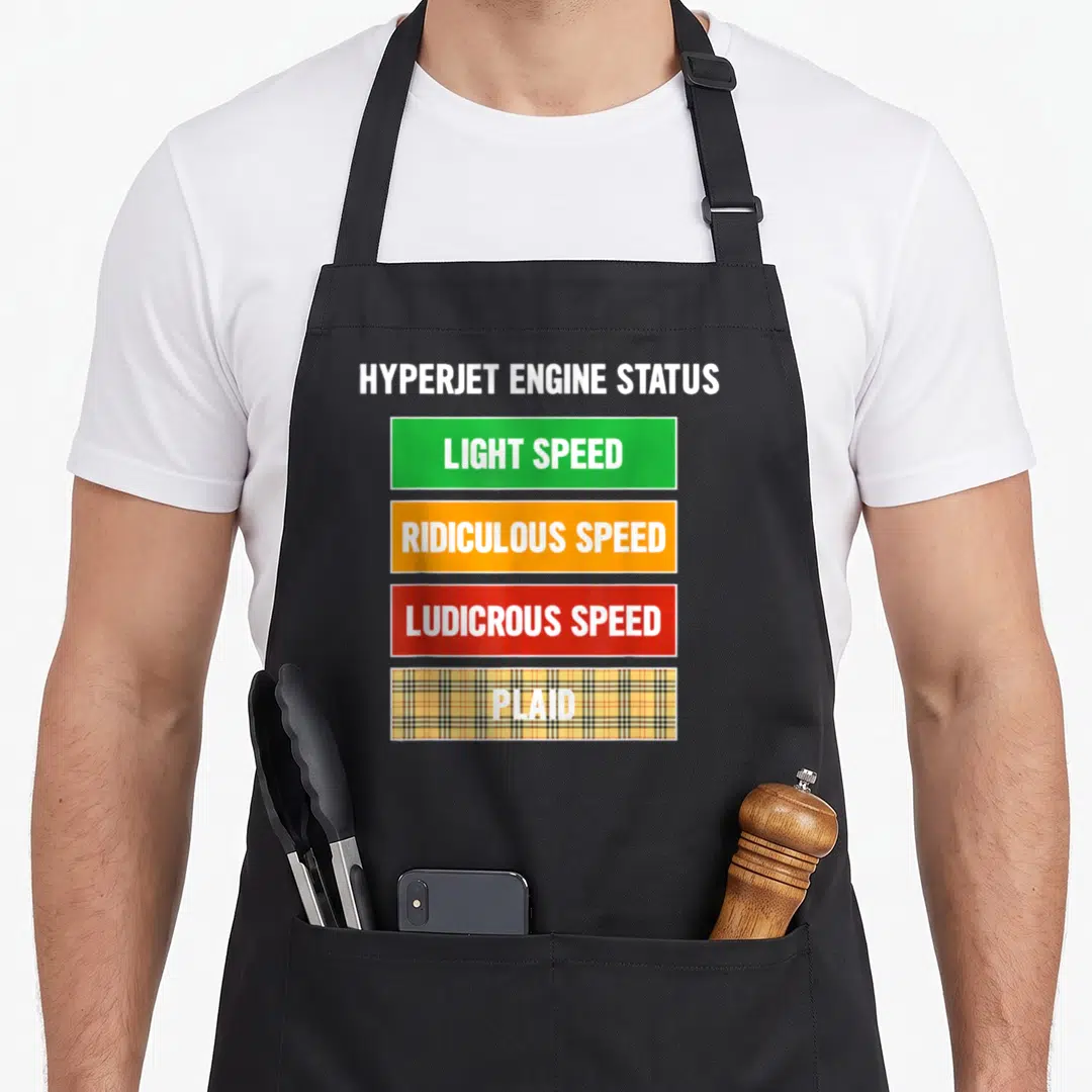 Nerdy the plaid apron - HYPERJET ENGINE STATUS text above green, orange, red bars and a yellow plaid bar reading PLAID — shown on a black cotton canvas apron against a white background