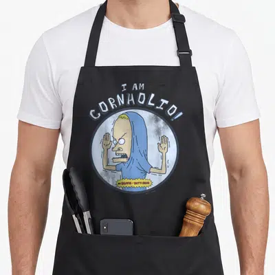 Cornholio distressed apron - Cartoon character with raised hands under I AM CORNHOLIO! text in blue white tan — shown on a black cotton canvas apron against a white background