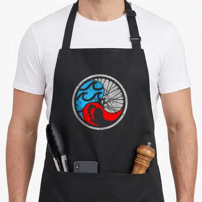 Swim bike apron - Circular yin yang with blue waves and red bike spokes in white border — shown on a black cotton canvas apron against a white background