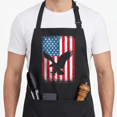 Flag independence 4th of july apron - Grey eagle silhouette over distressed red white and blue USA flag — shown on a black cotton canvas apron against a white background