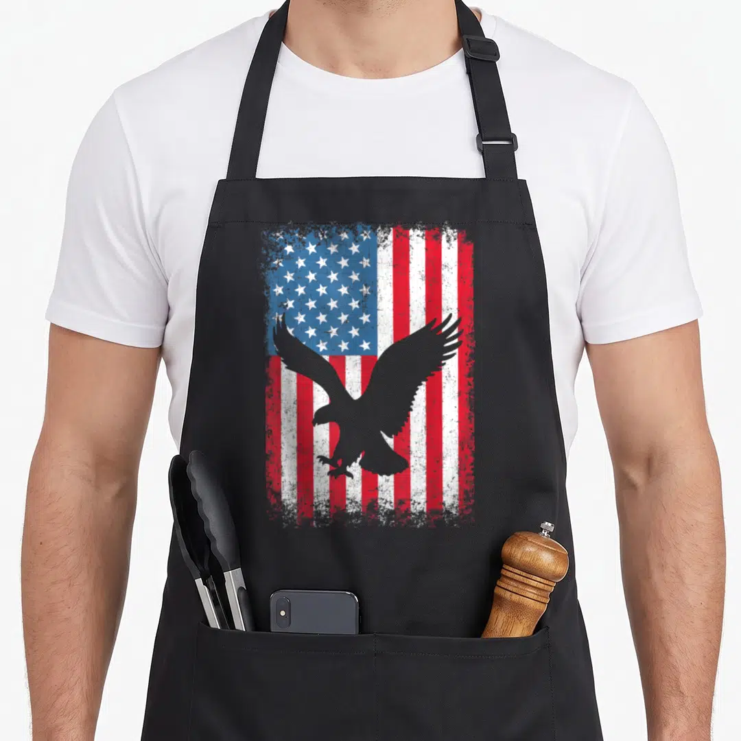 Flag independence 4th of july apron - Grey eagle silhouette over distressed red white and blue USA flag — shown on a black cotton canvas apron against a white background