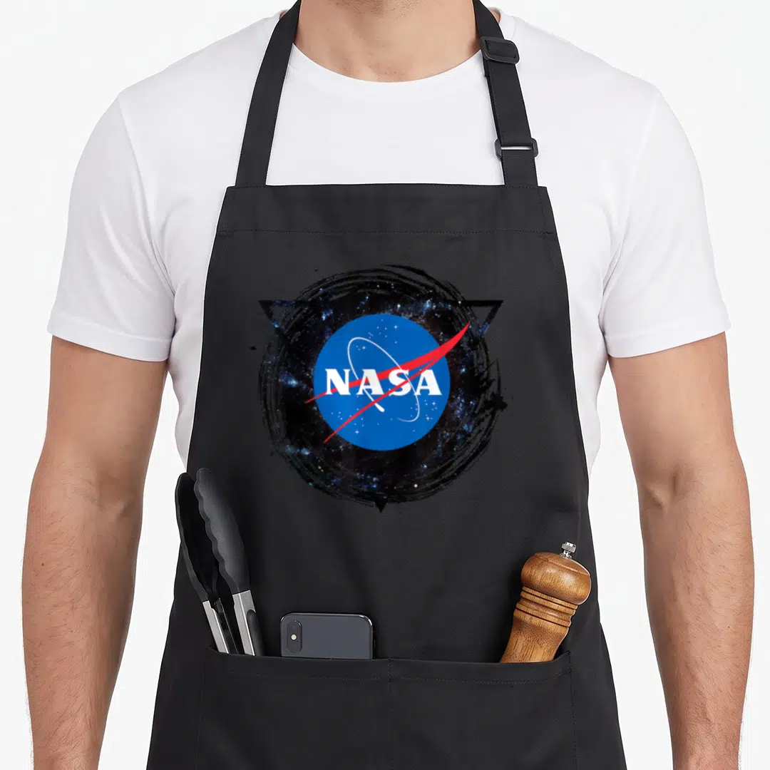 Funny nasa apron - NASA logo in blue white red black inside brushstroke and triangle — shown on a black cotton canvas apron against a white background
