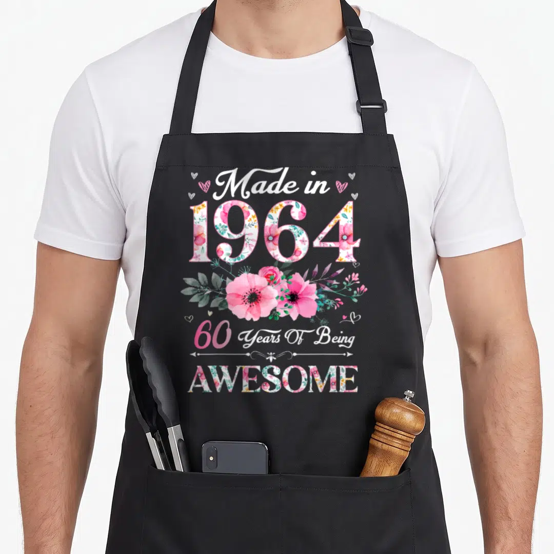 60th birthday vintage floral apron - Pink watercolor flowers fill 1964 text with Made in 1964 and 60 Years Of Being — shown on a black cotton canvas apron against a white background