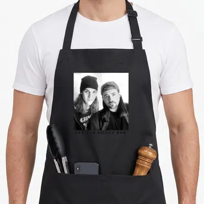 Jay simple apron - Black and white photo of two men with JAY AND SILENT BOB text below — shown on a black cotton canvas apron against a white background