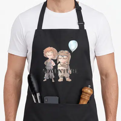 Adventure carl and ellie apron - Two cartoon children standing beside a blue balloon with text overlay — shown on a black cotton canvas apron against a white background