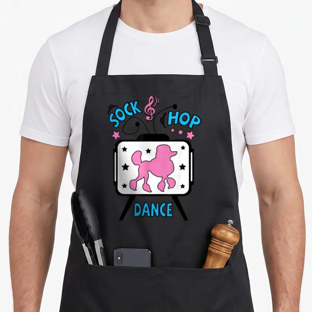 Poodle rockabilly apron - Jukebox with pink poodle silhouette and blue SOCK HOP DANCE text in cartoon style — shown on a black cotton canvas apron against a white background